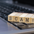 wooden cubes on a laptop that spell scam